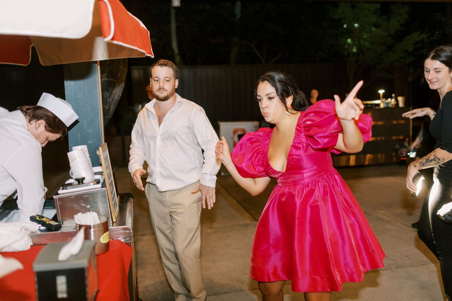 A group of people dancing together at what appears to be a wedding celebration or party under dim lighting.
