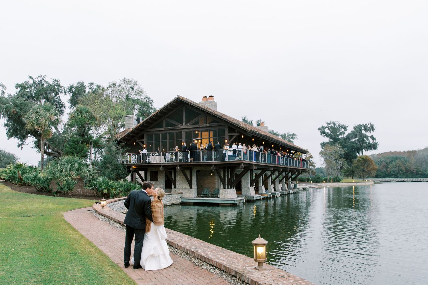 A rustic wooden lodge with balconies overlooks a serene lake surrounded by green landscaping and trees at Frederica Golf Club in St. Simons.