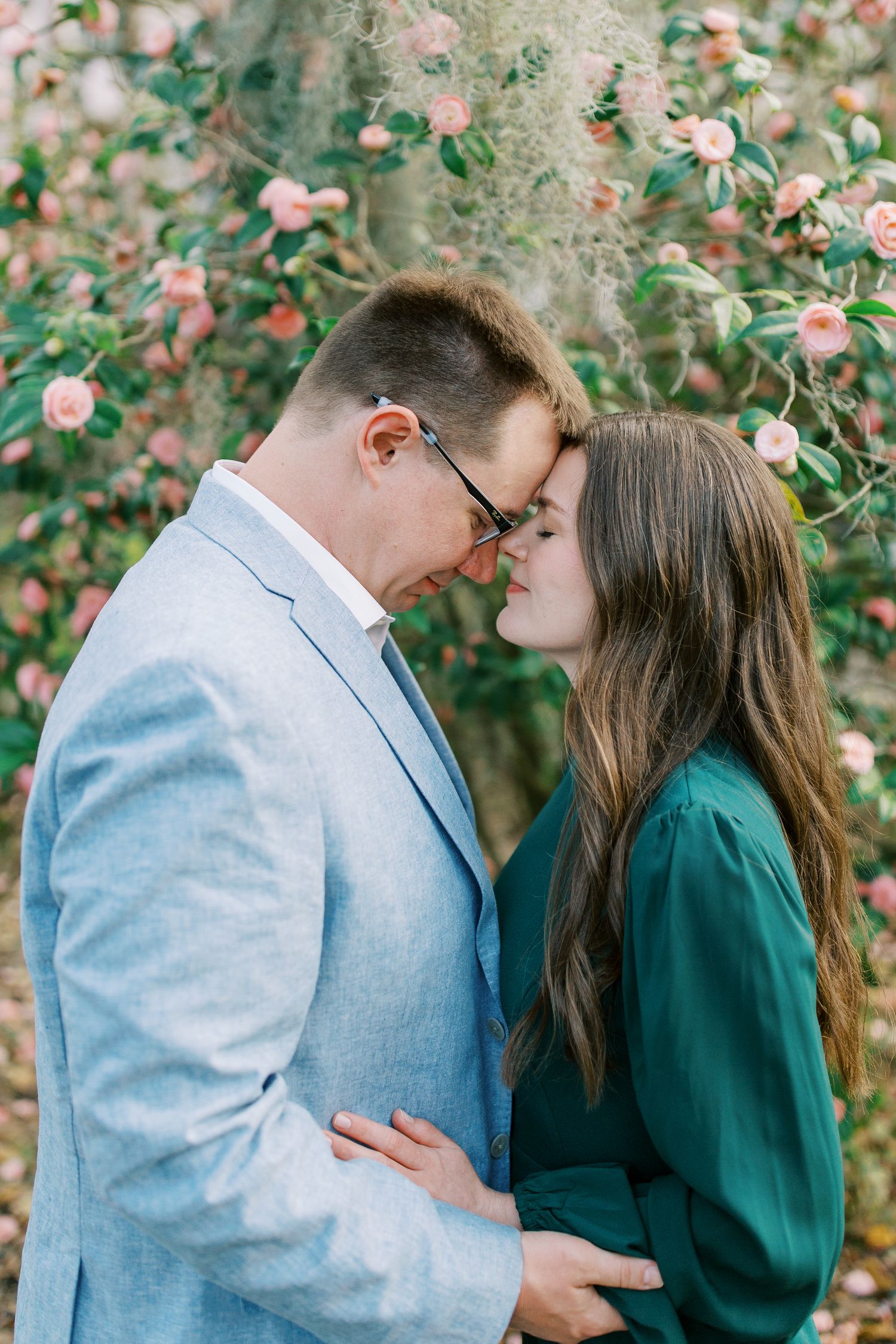 Sweet couple embraces near blooming pink flowers in garden setting.