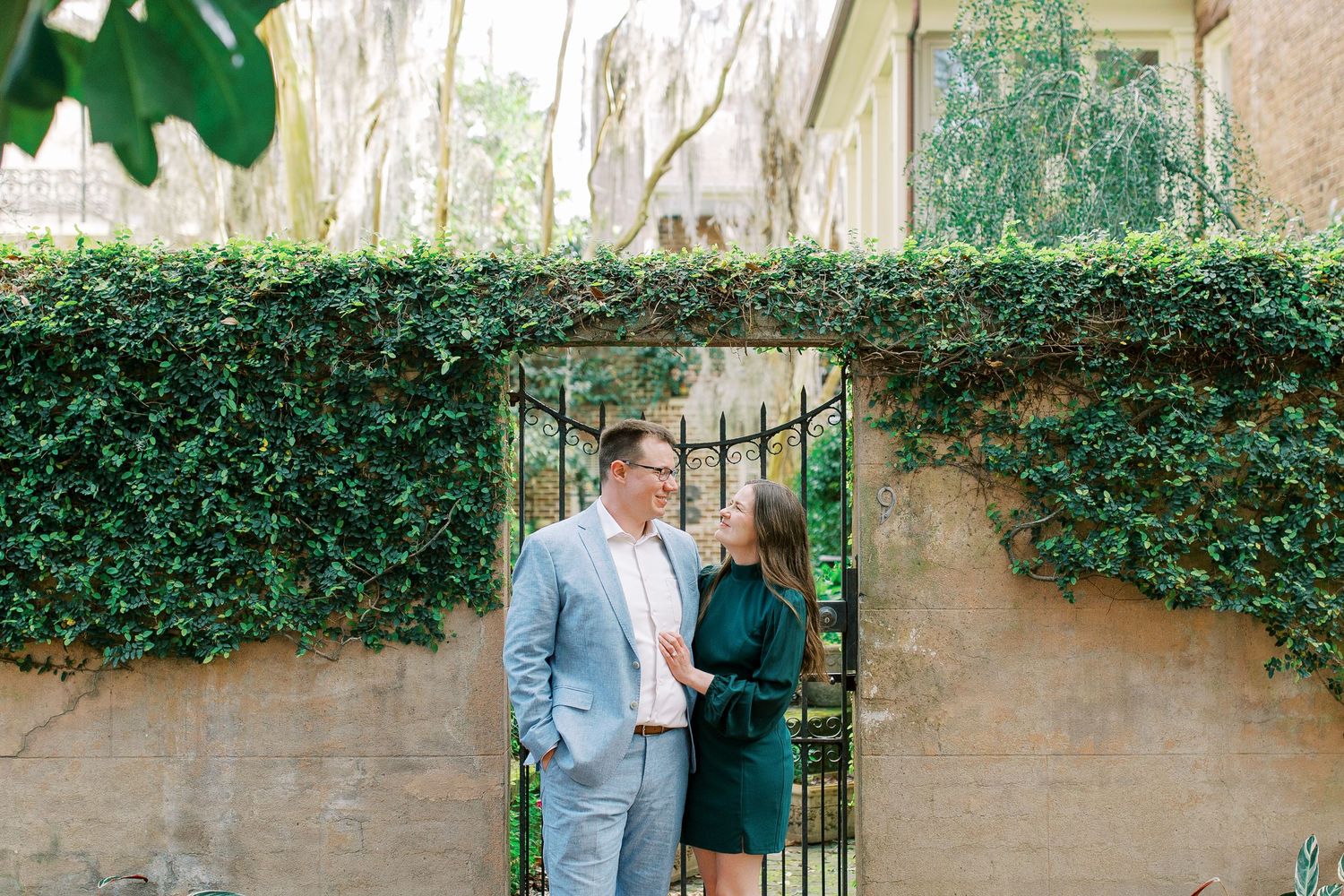 A couple poses by an ivy-covered garden gate entrance.