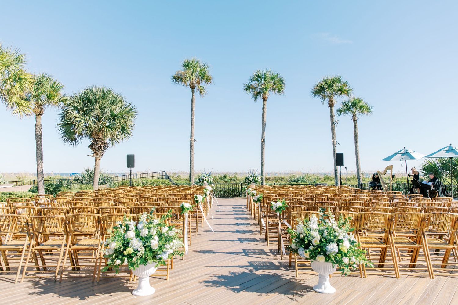 Chairs arranged for an outdoor beach wedding ceremony with palm trees and floral arrangements along the aisle at The Westin in Hilton Head.