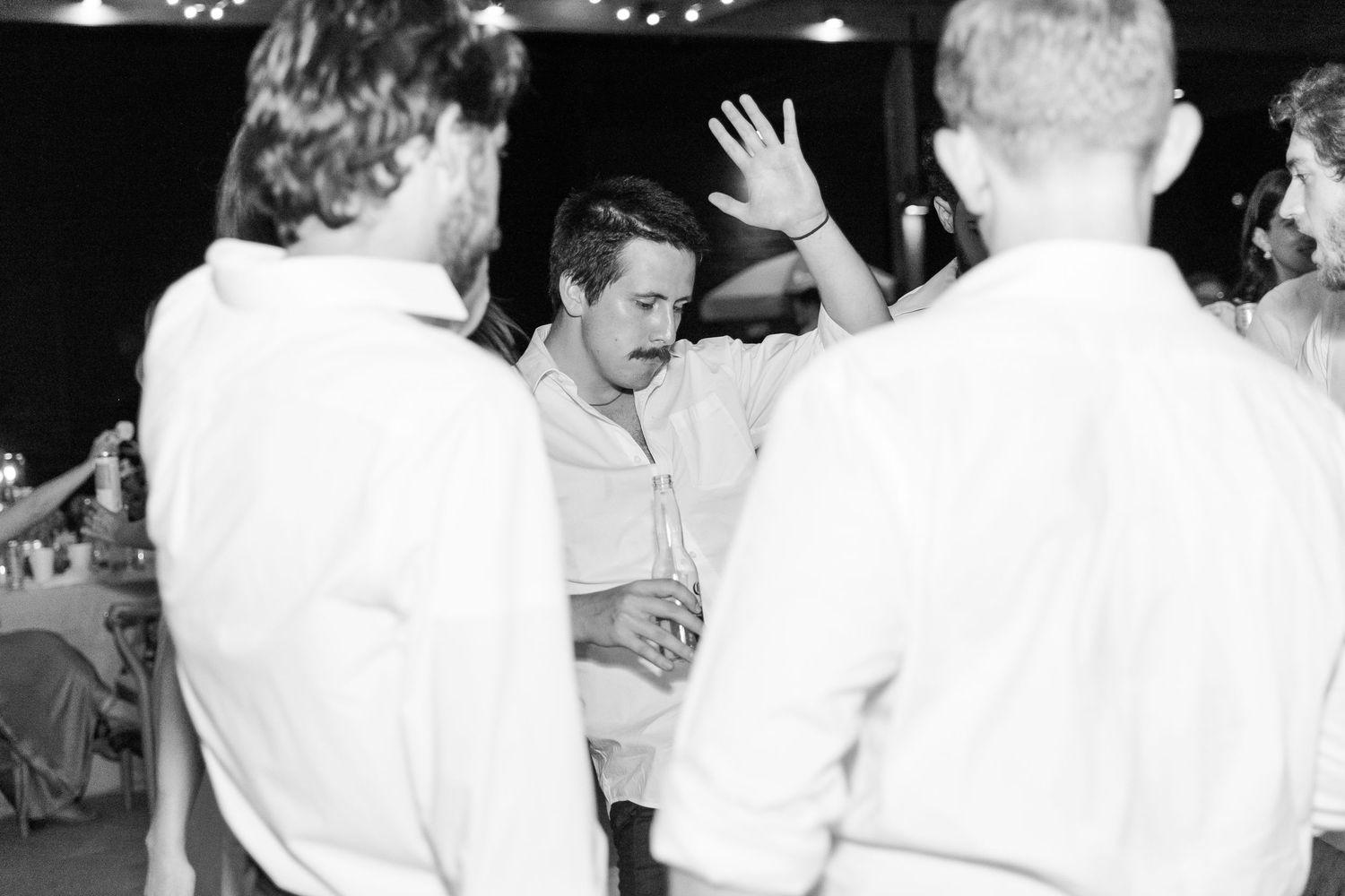 Black and white photo of wedding reception guests dancing and celebrating.