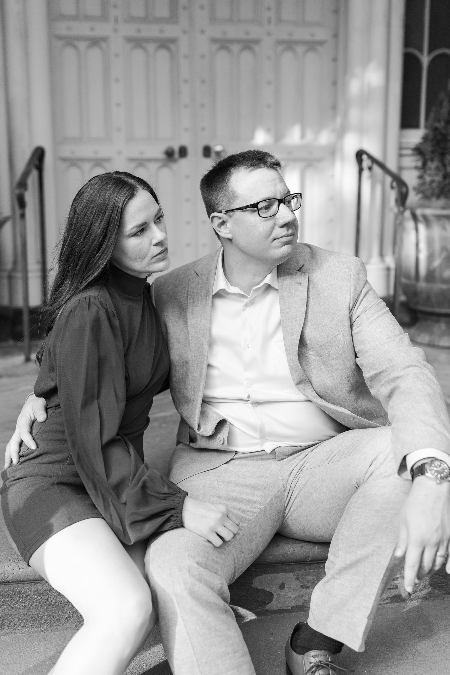A black and white candid photo of a couple sitting on stone steps.