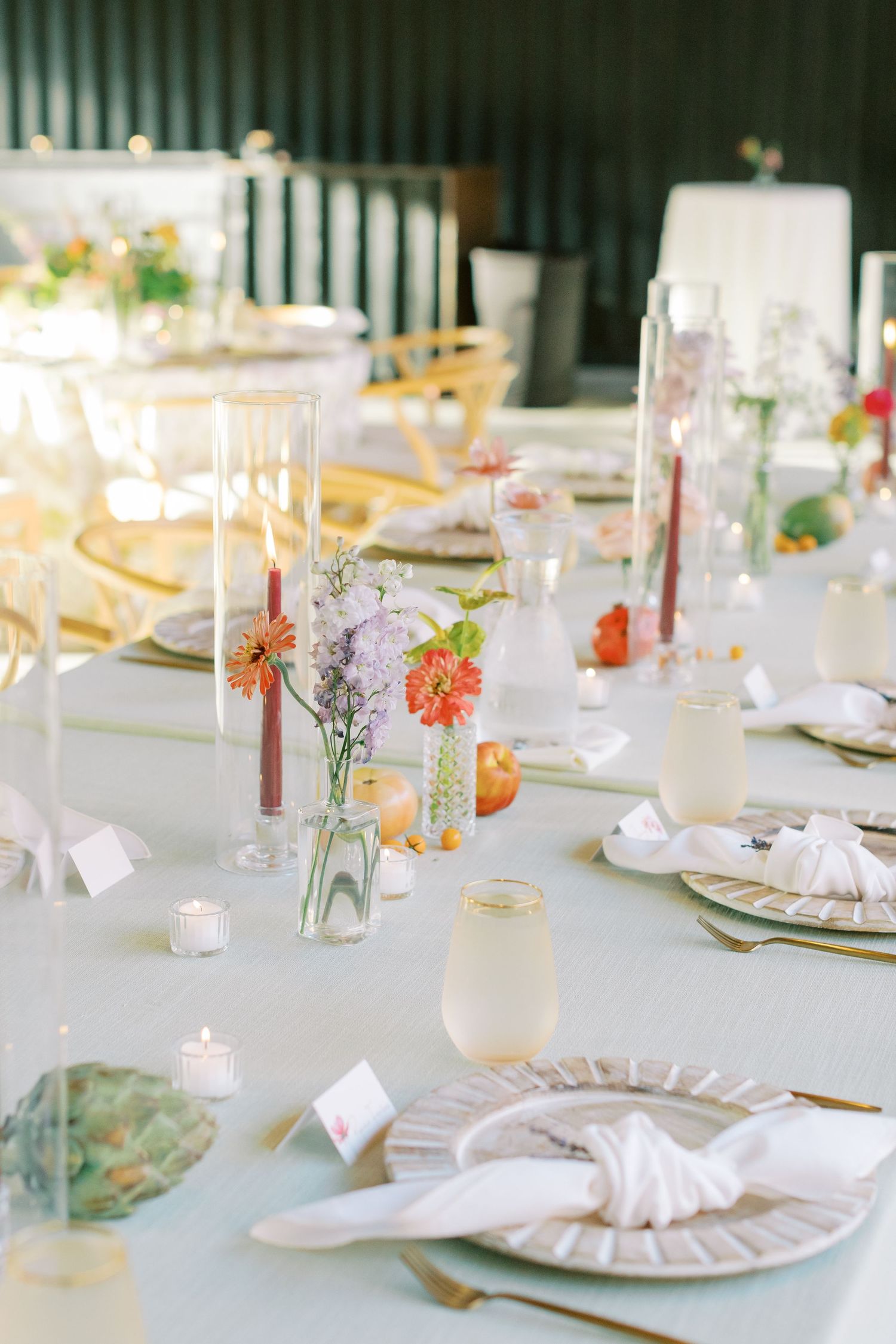 An elegant wedding table setting with delicate floral centerpieces in glass vases and soft candlelight.