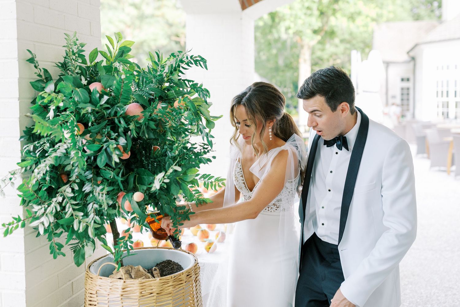 Bride and groom in formal attire unburying bourbon that they buried to keep the rain away on their wedding day.
