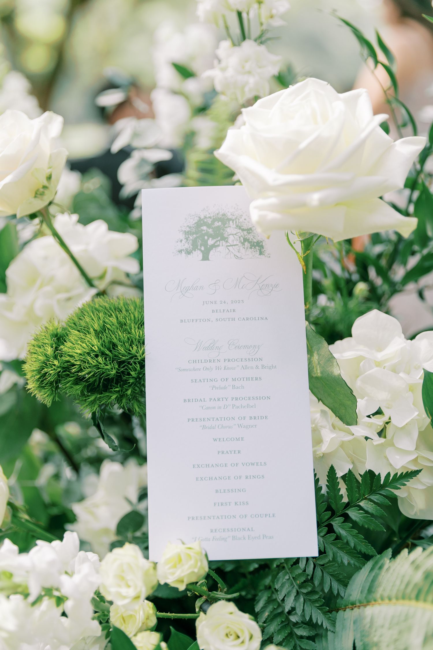 Elegant white wedding ceremony outline nestled among white roses and green florals in a romantic garden setting.