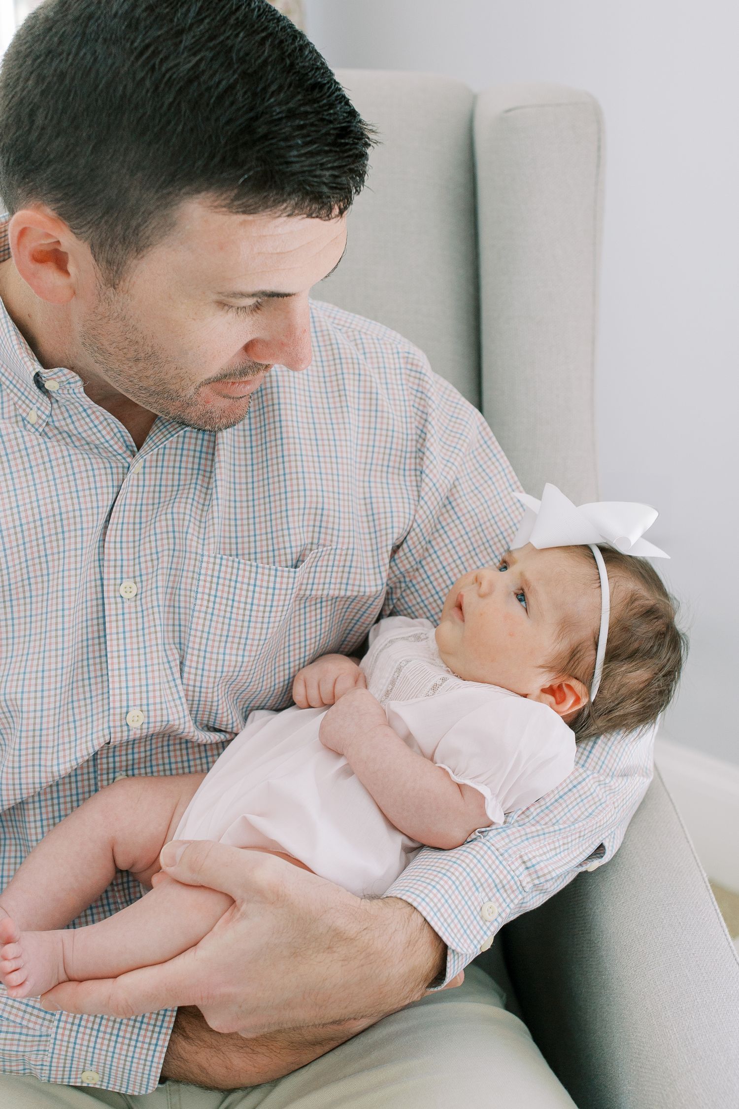 Close-up view of tender moment between adult and baby in gray chair.