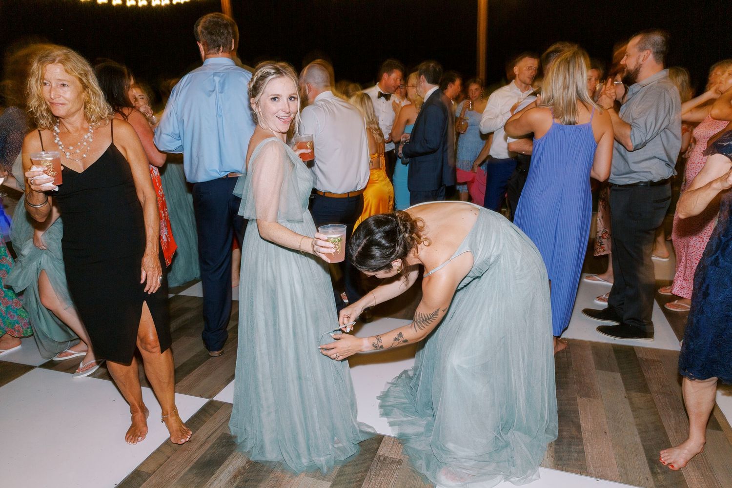 Wedding guests in formal attire dancing on outdoor dance floor at night.