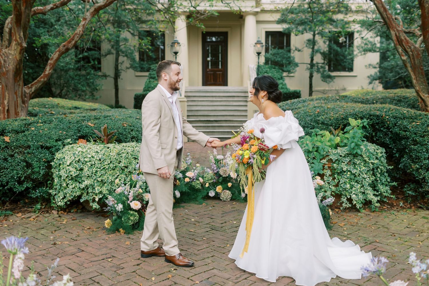Wedding couple having a sweet moment in front of a beautiful historic mansion entrance.