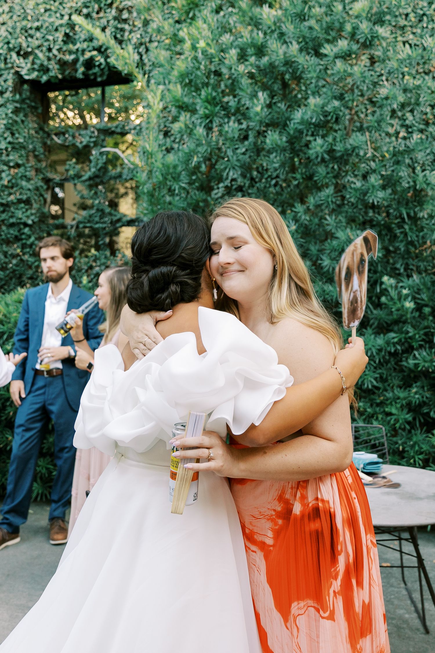 Wedding celebration moment captured outdoors with guests sharing warm embraces.