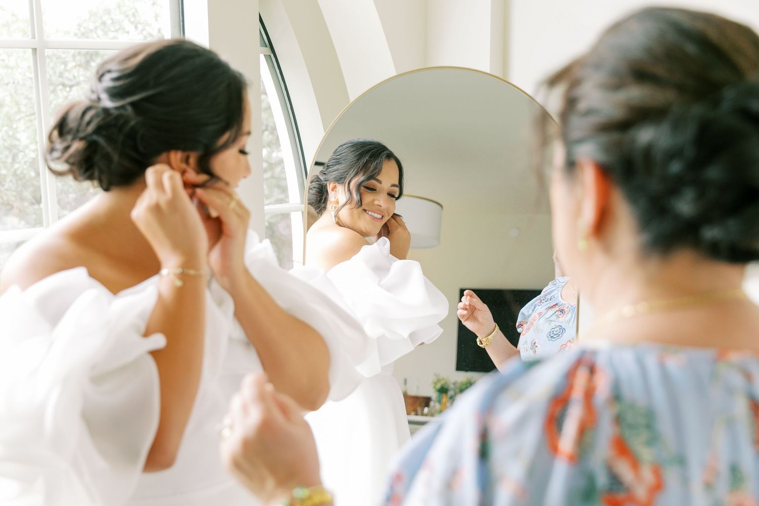 Wedding morning preparations with people gathered in a bright white space with natural light.