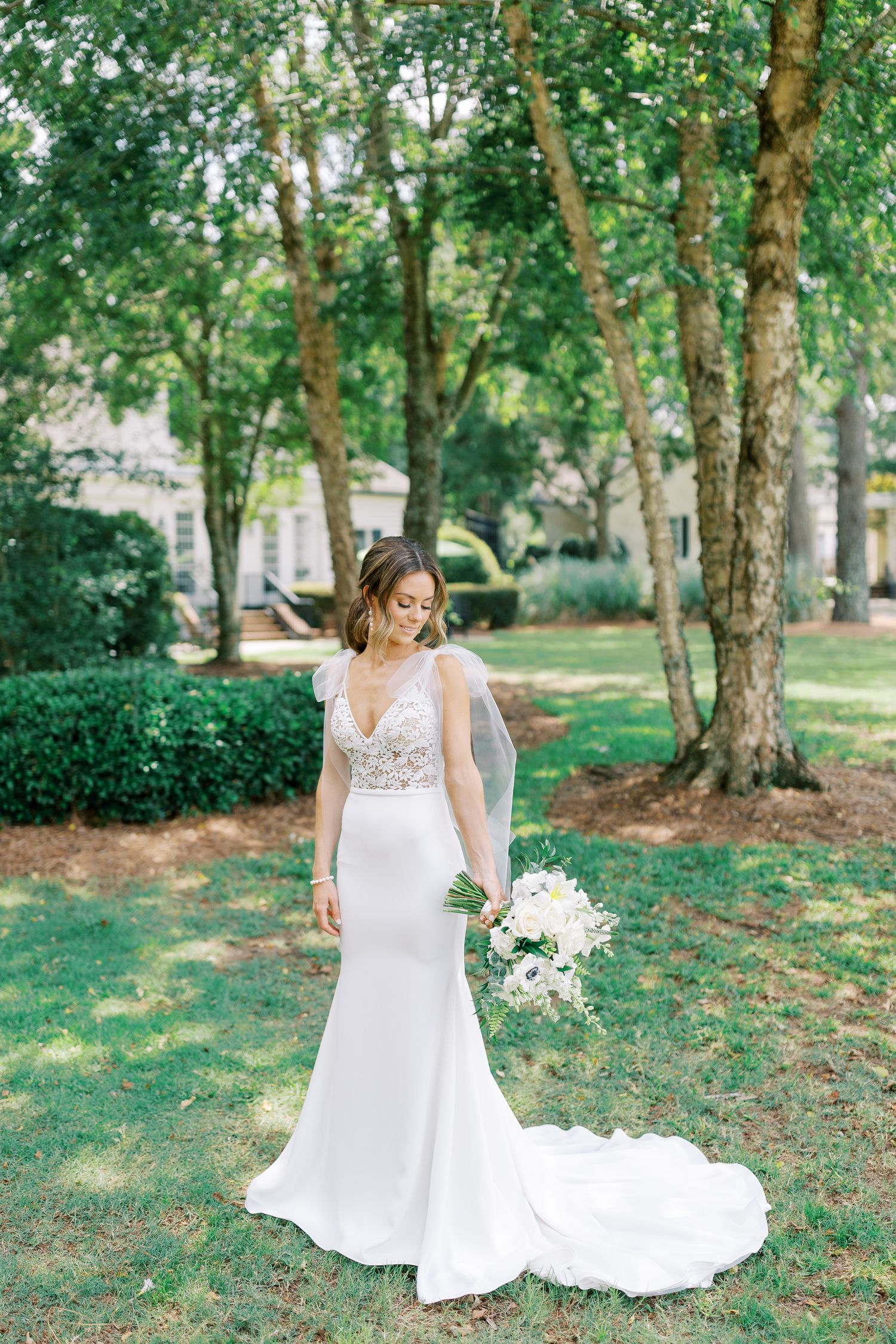 A wedding gown with delicate lace detailing photographed in a serene outdoor garden setting.