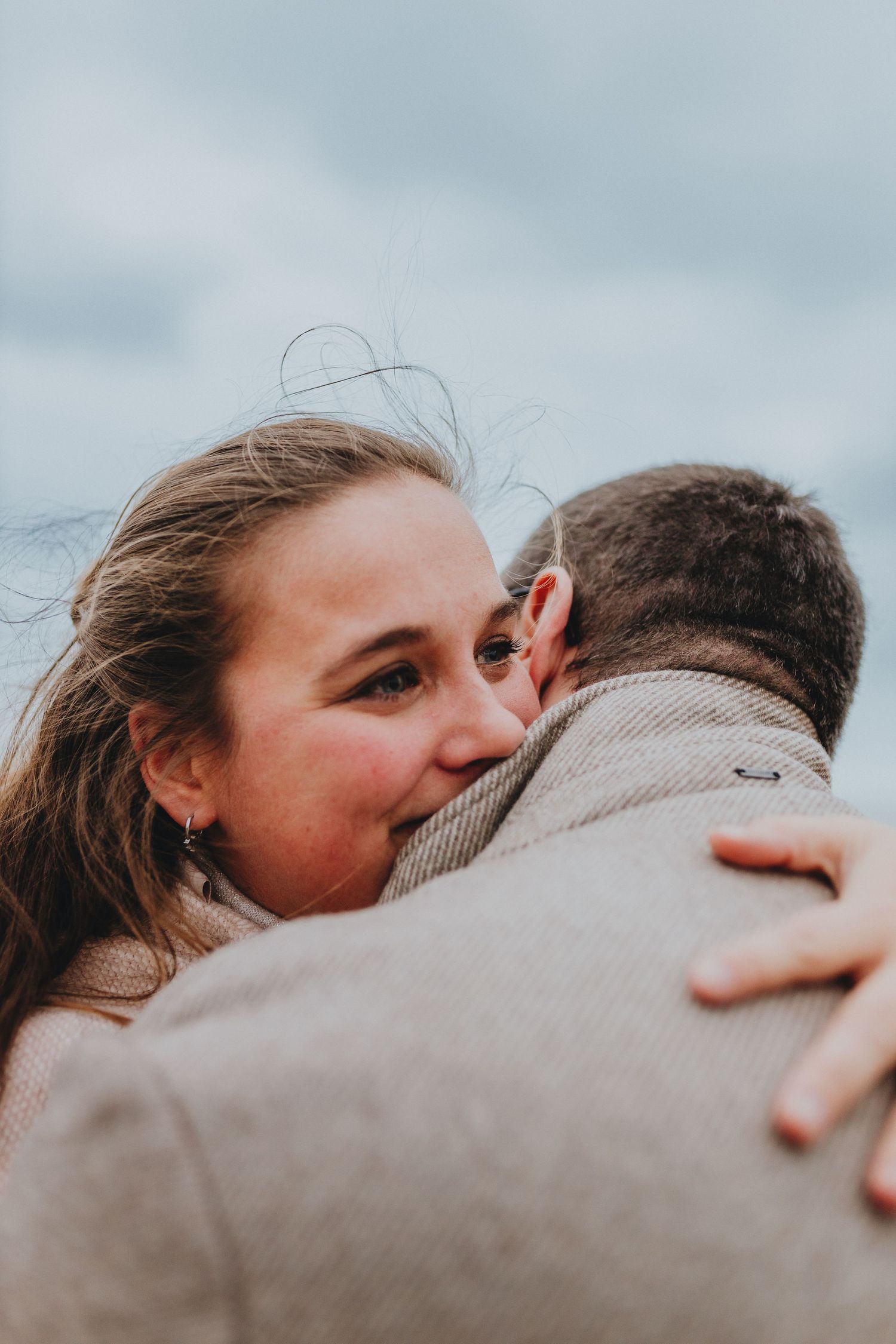 vrouw die oprecht emotioneel is na een verrassing verloving aanzoek koppel fotoshoot aan de zee van De Haan