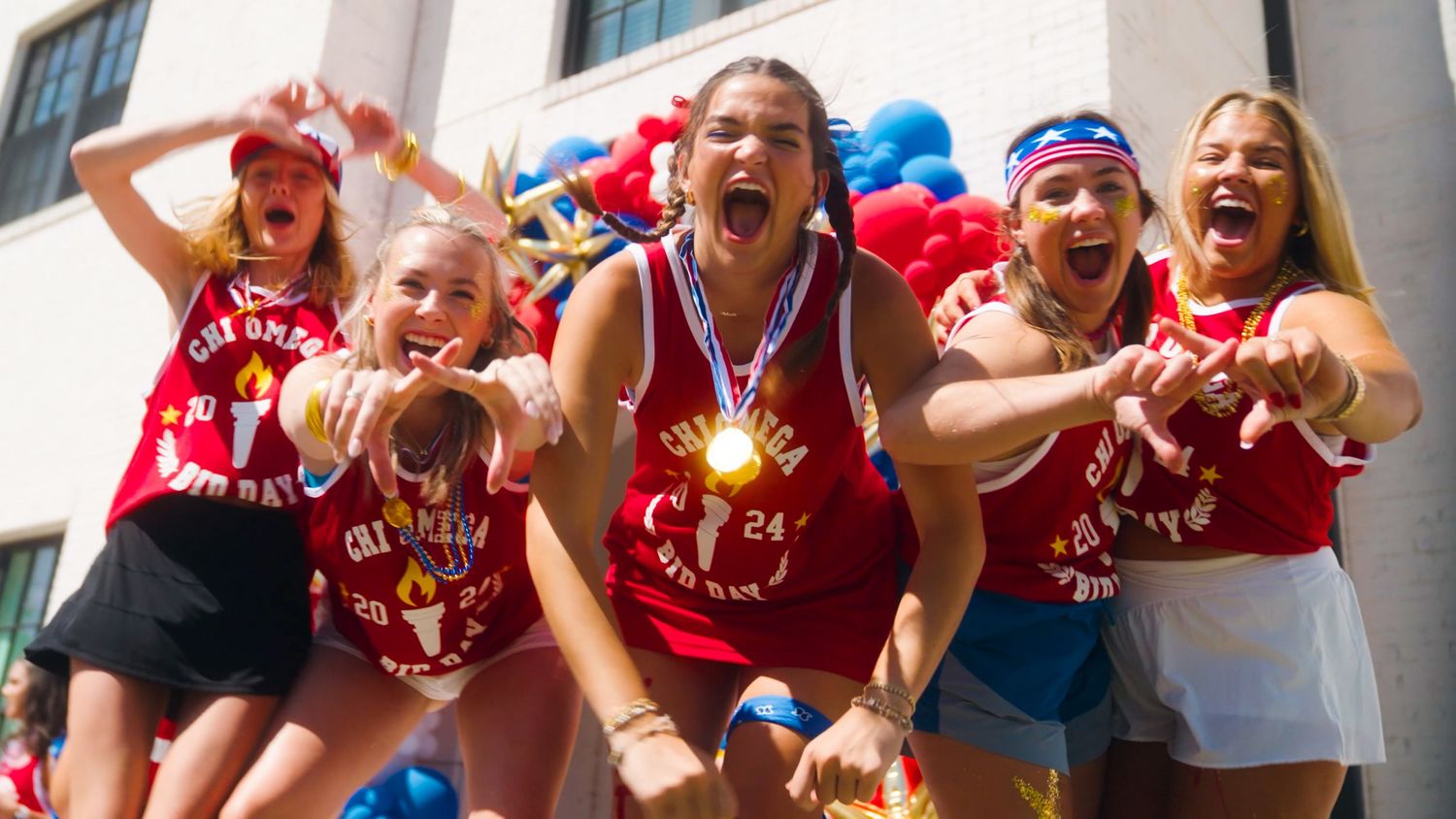 Group of excited fans in red sports jerseys cheering and celebrating together during a baseball game.