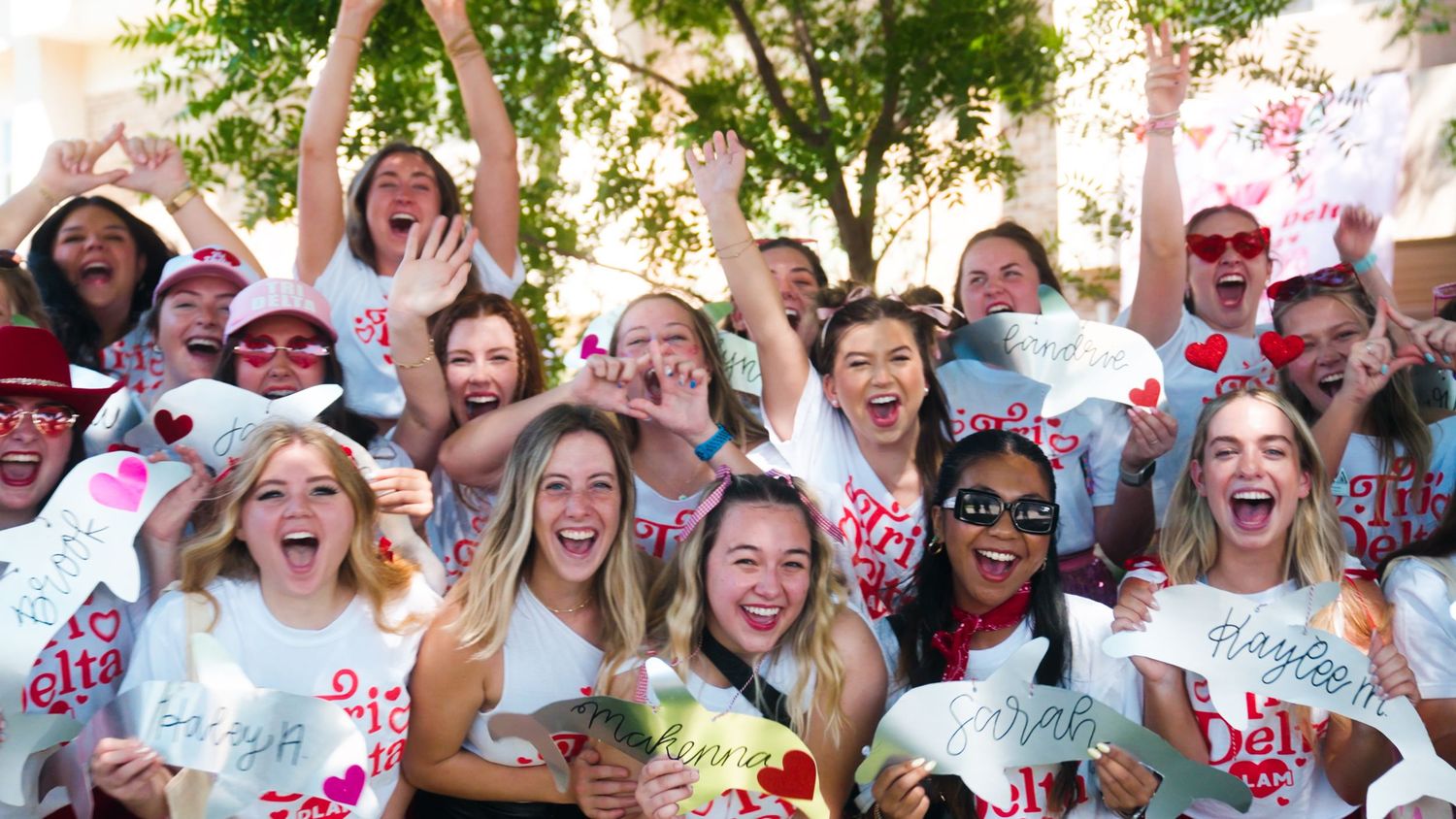 A crowd of people smiling and celebrating together covered in colorful powder during a color run event outdoors.