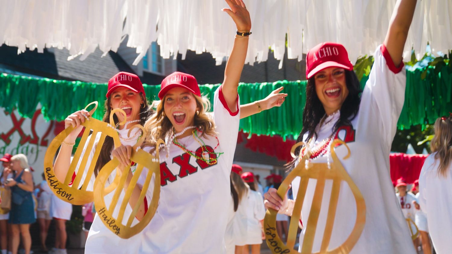 A group performs a vibrant cultural dance routine wearing red hats and white clothing while standing in line.