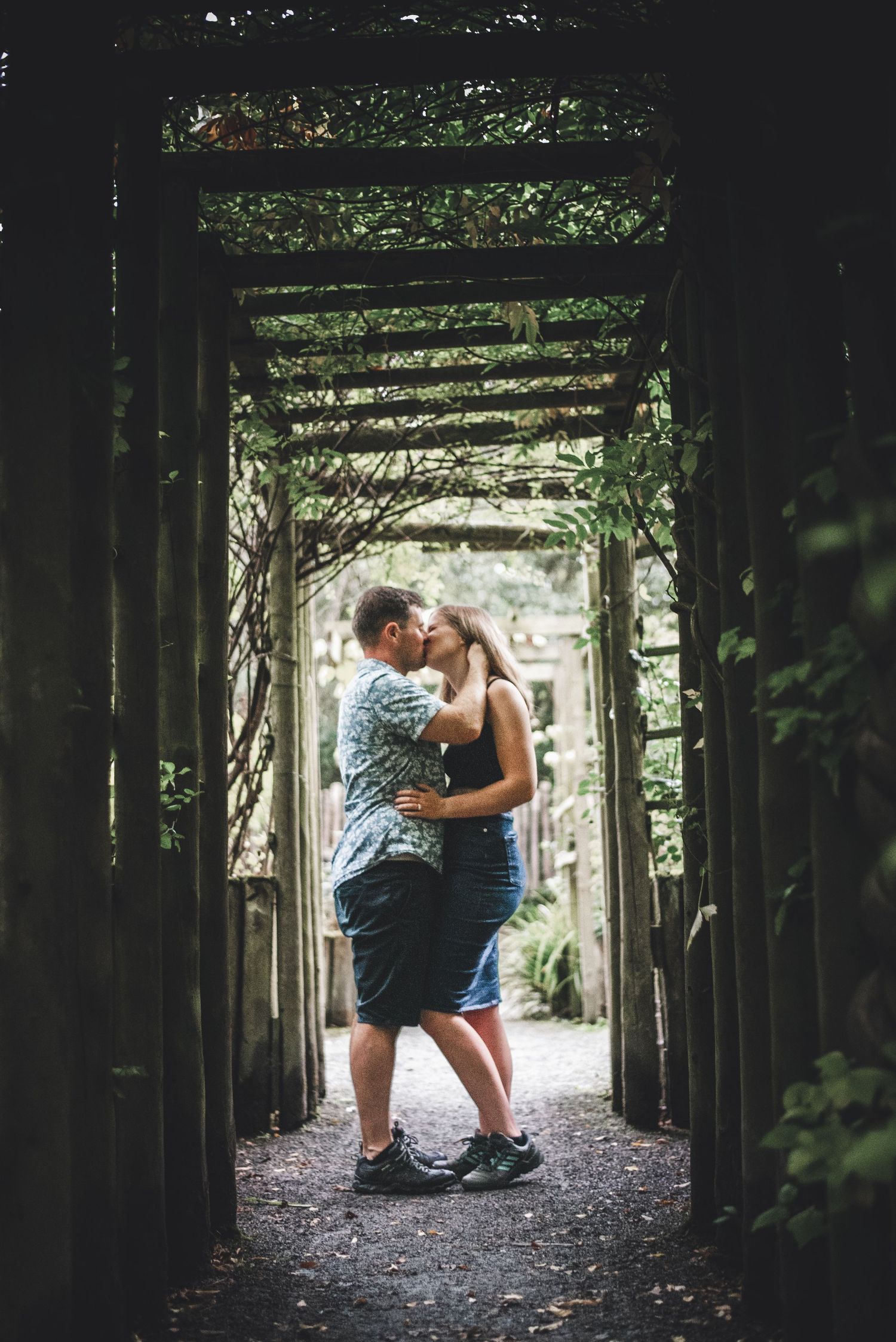 A romantic moment shared between two people under a vine-covered archway.