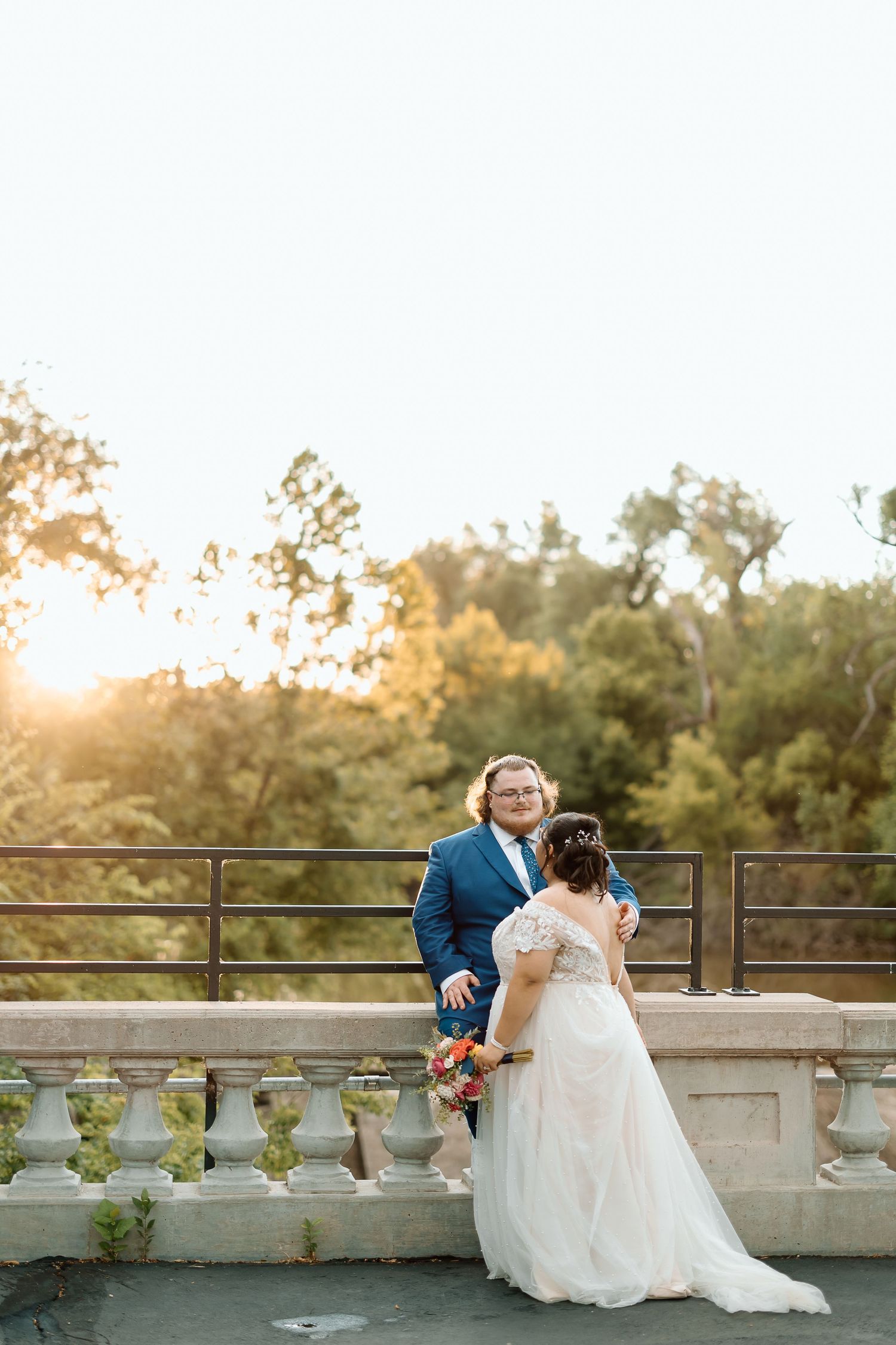 Wedding couple sharing a sunset moment on an ornate stone balcony.