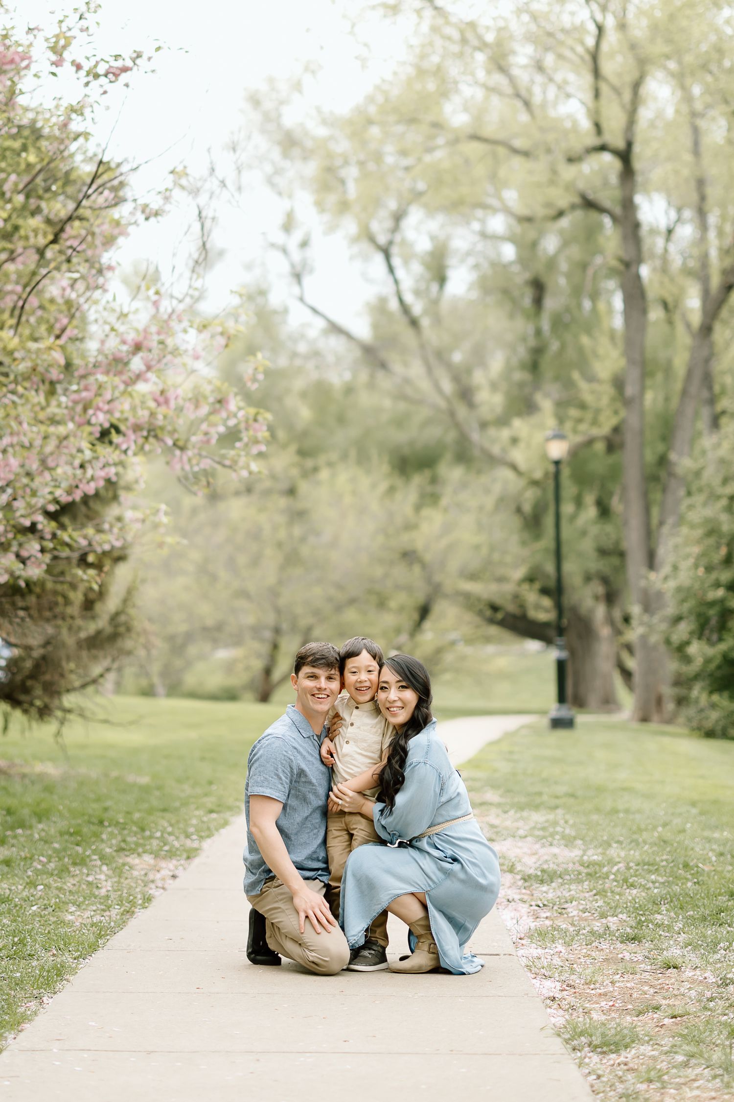 Family portrait on walking path with blooming spring trees in background.