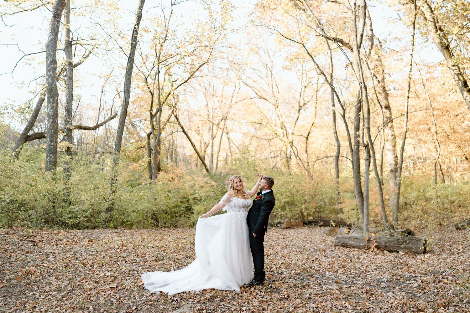 A romantic wedding photo in an autumn forest with golden leaves and natural lighting.