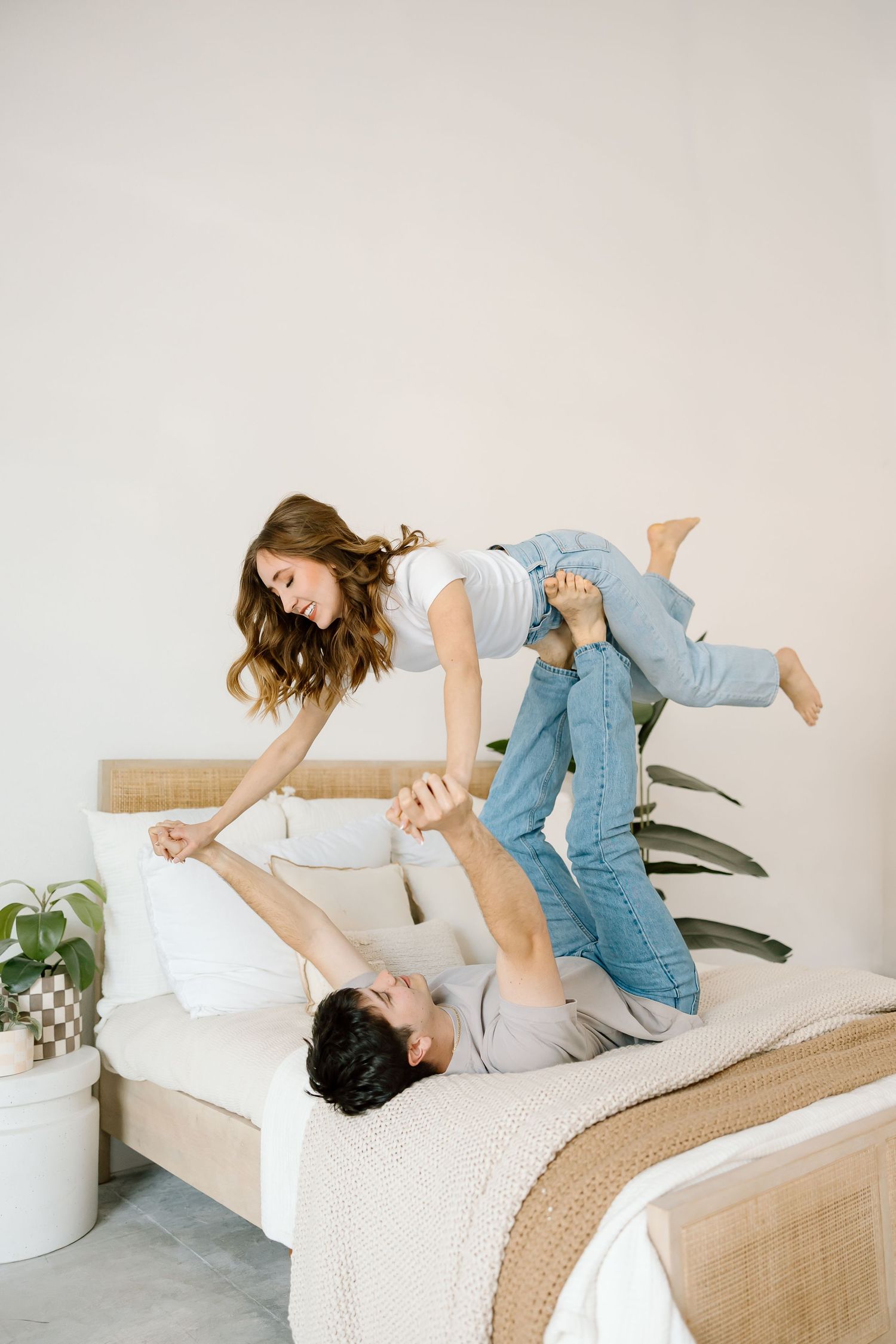 Playful scene in bright bedroom with jeans and casual attire.