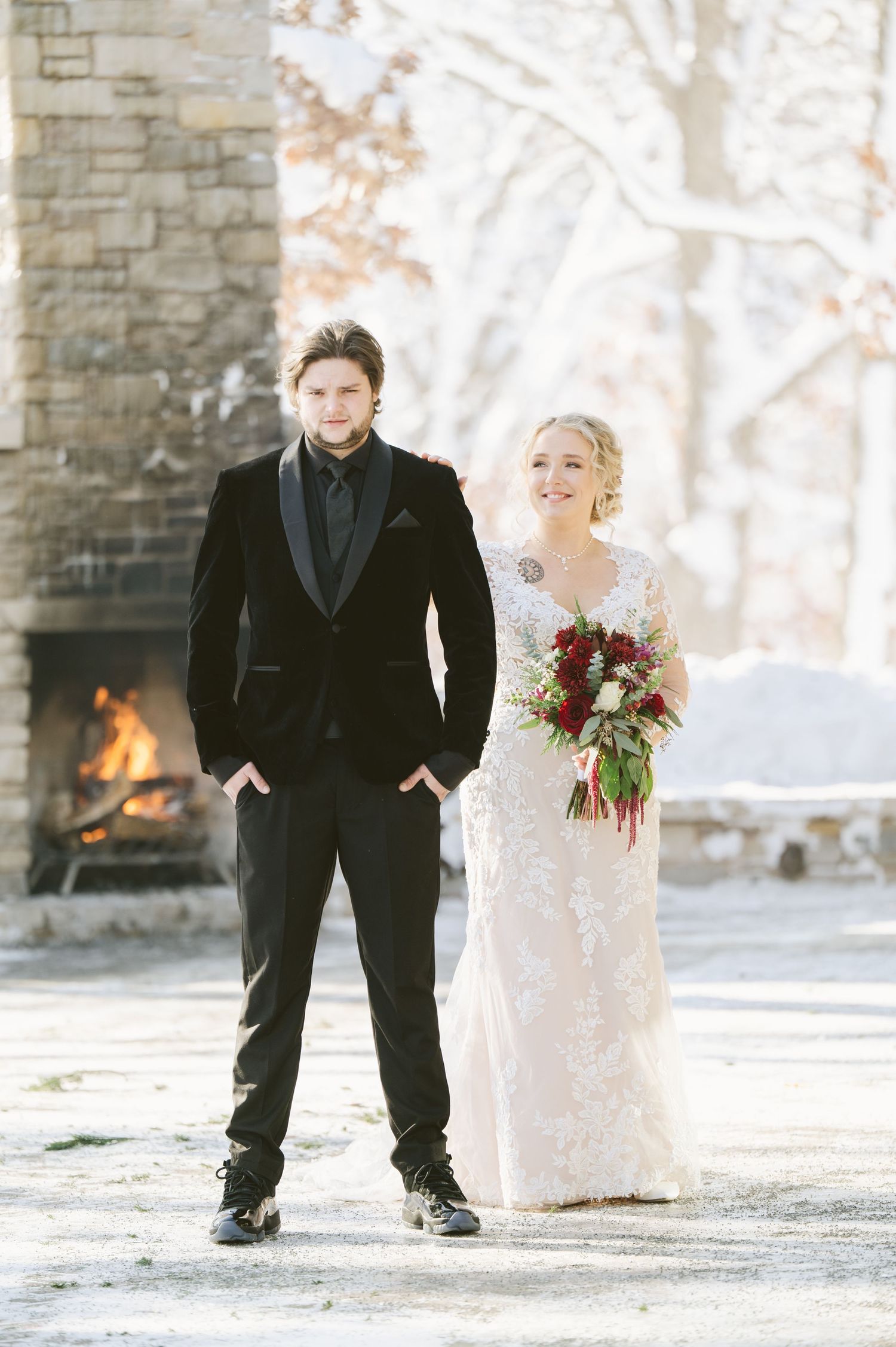 St Anthony First look A couple shares joyful moments on their winter wedding day in front of a stone wall background.