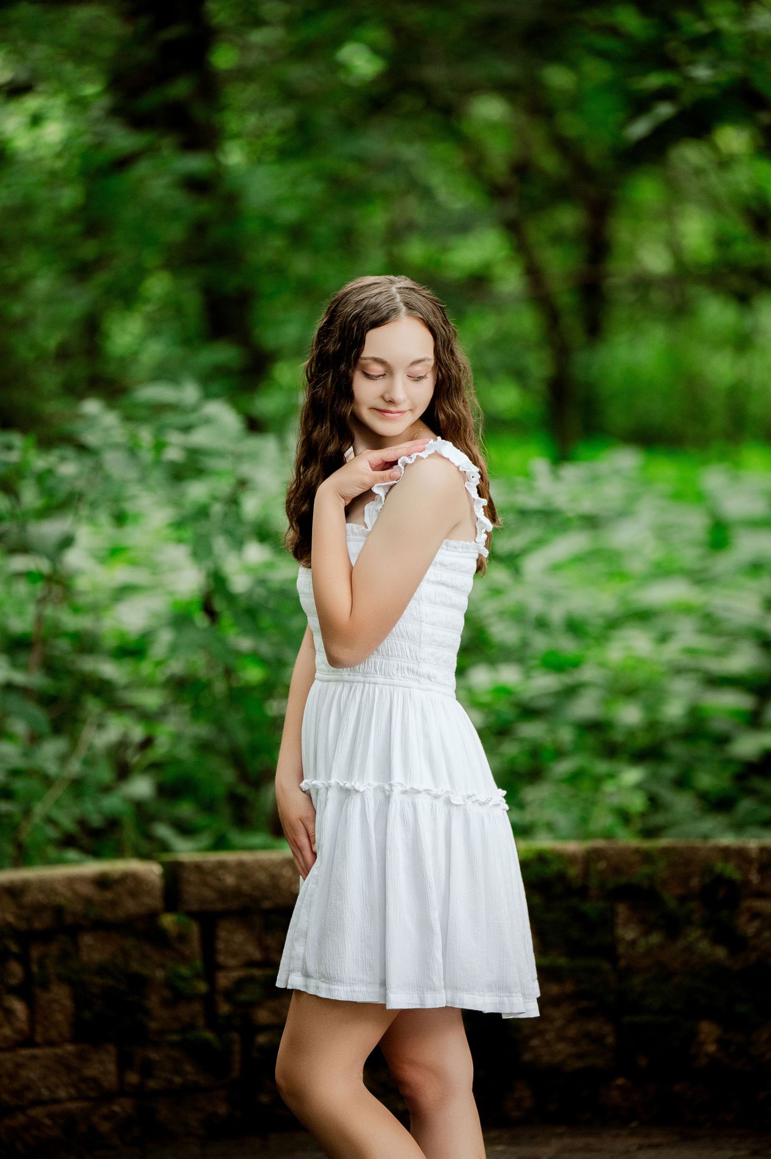 Senior Portrait in Central MN Playful white dress photoshoot in garden setting with stone wall.
