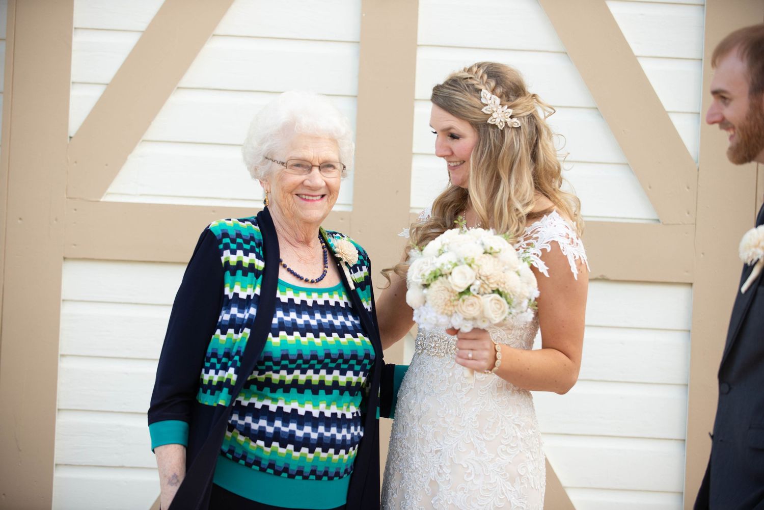 A touching wedding moment shared against a white wall background with floral bouquet. Milaca Minnesota Weddings