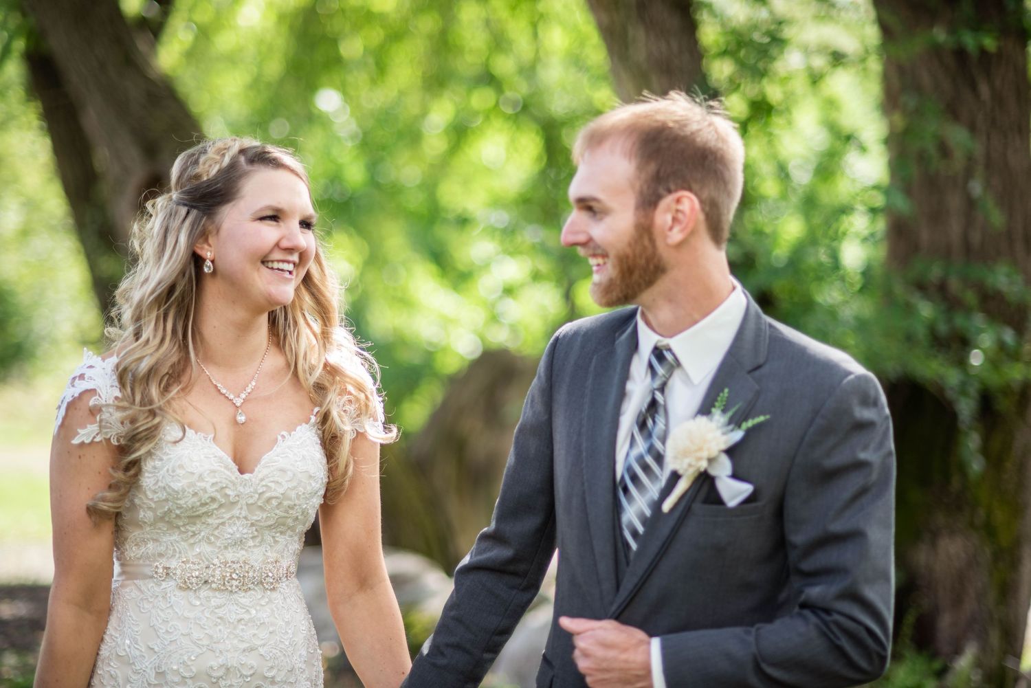 Wedding couple sharing joyful moment together under green trees in summer garden.