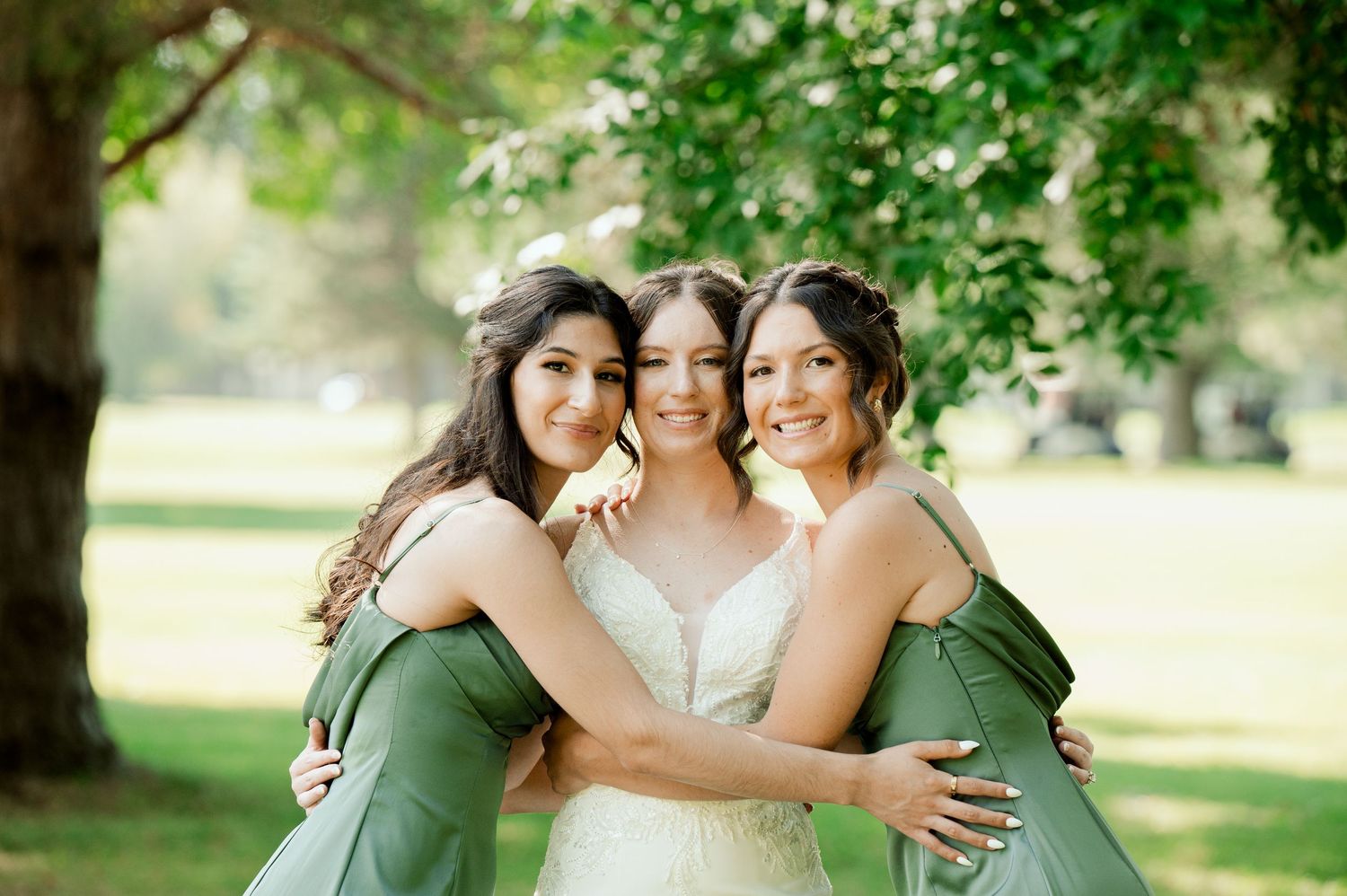 The Grands at Mulligans- Wedding Photos: Three bridesmaids in matching green dresses share an emotional embrace during outdoor