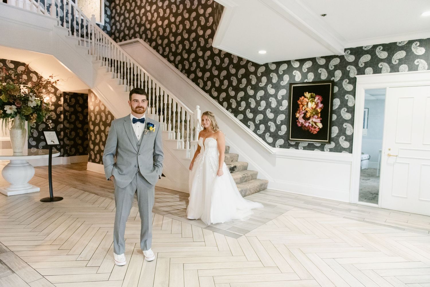 Elegant wedding venue interior with sweeping staircase and patterned wallpaper.