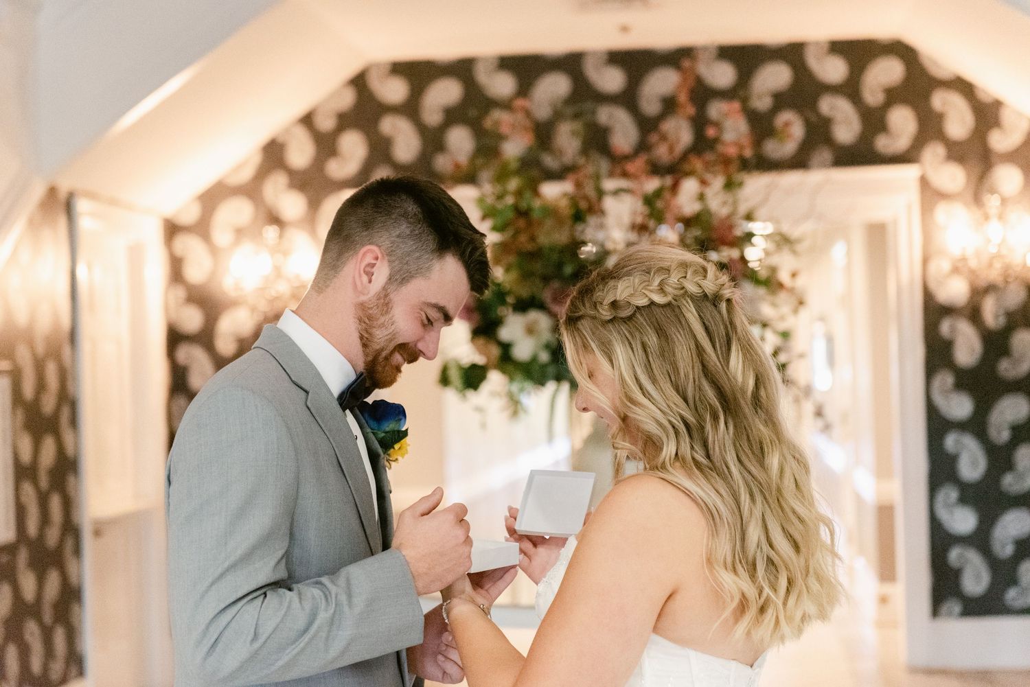 A tender wedding ceremony moment with couple exchanging vows under an ornate backdrop with fairy lights.