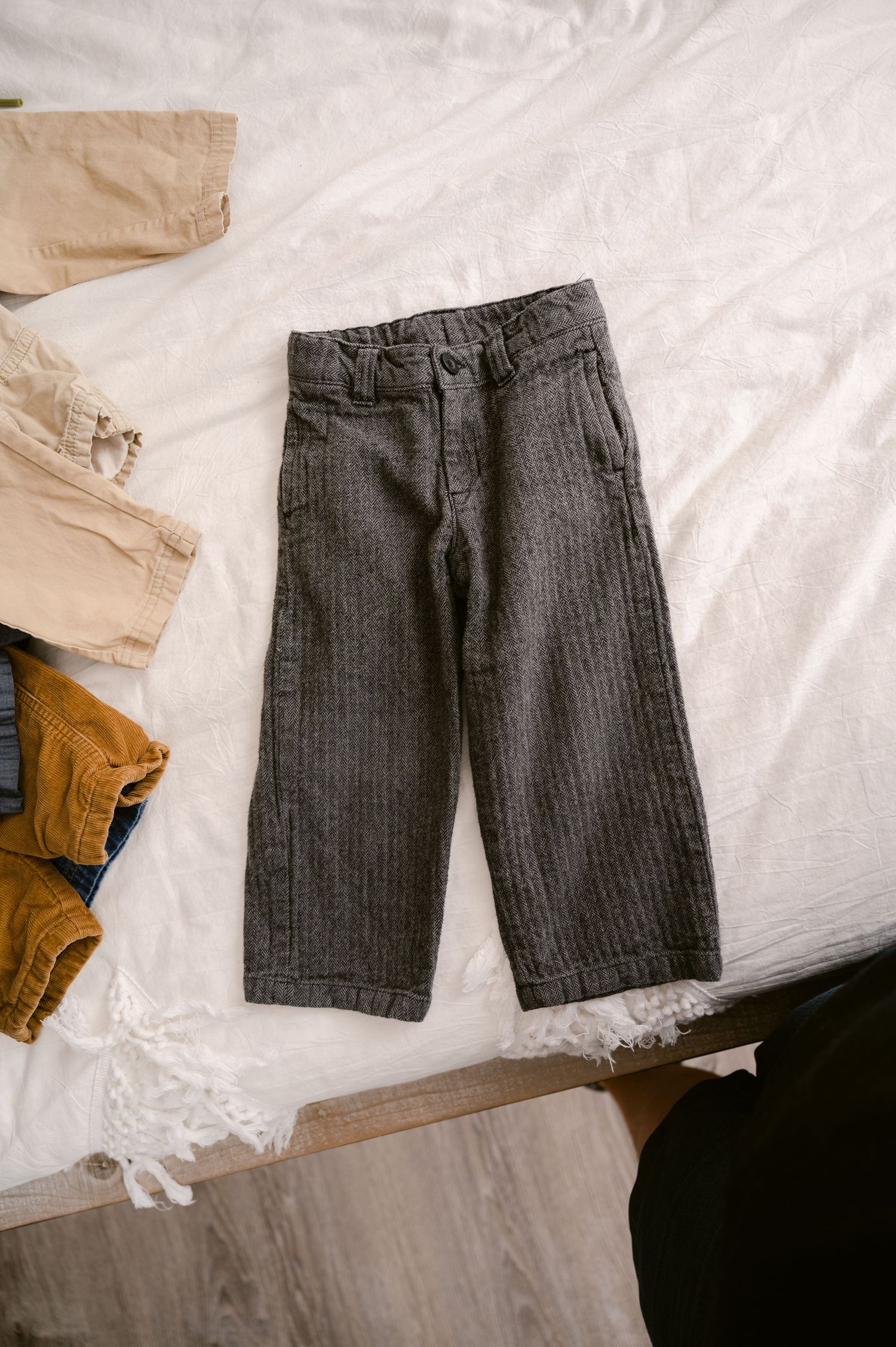 A pair of charcoal gray corduroy wide-leg cropped pants laid flat on white fabric.