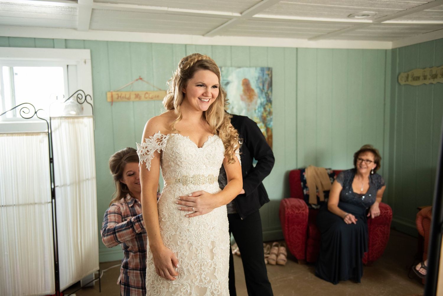 A person getting ready in a mint green room with wedding preparations underway.