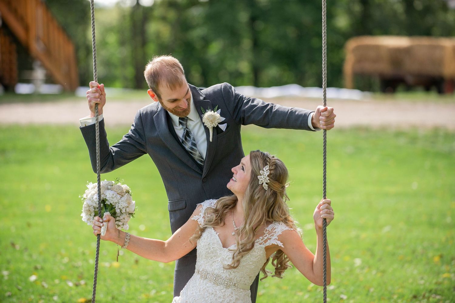 Playful wedding photo of couple on wooden swing set in outdoor garden setting. Rum River Barn Milaca Minnesota Weddings
