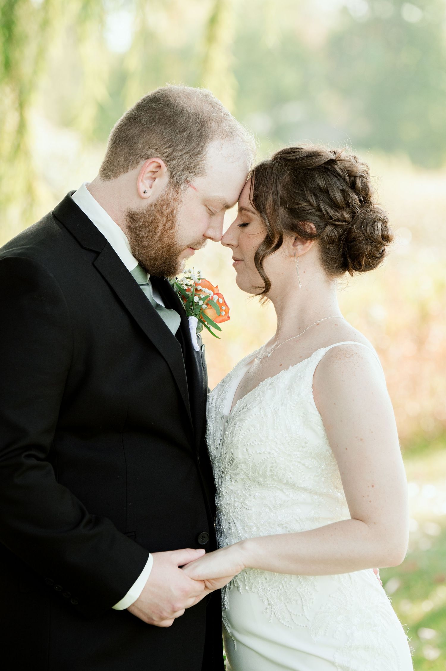 A tender moment between newlyweds as they embrace beneath a weeping willow tree.