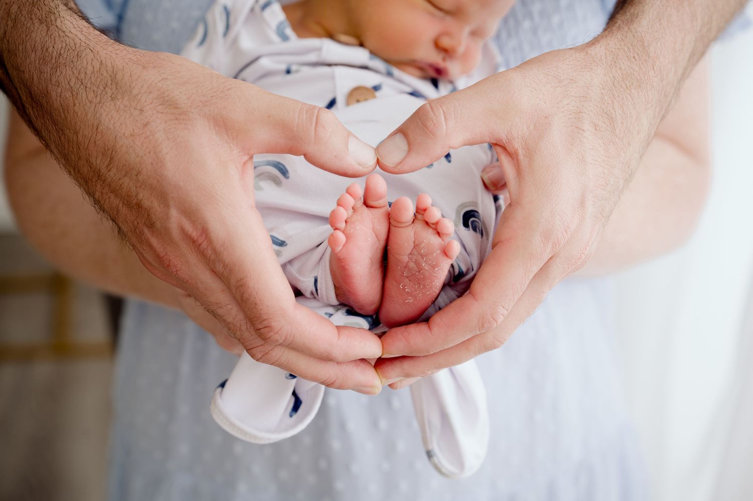 Close-up of tiny newborn feet being gently held by adult hands.