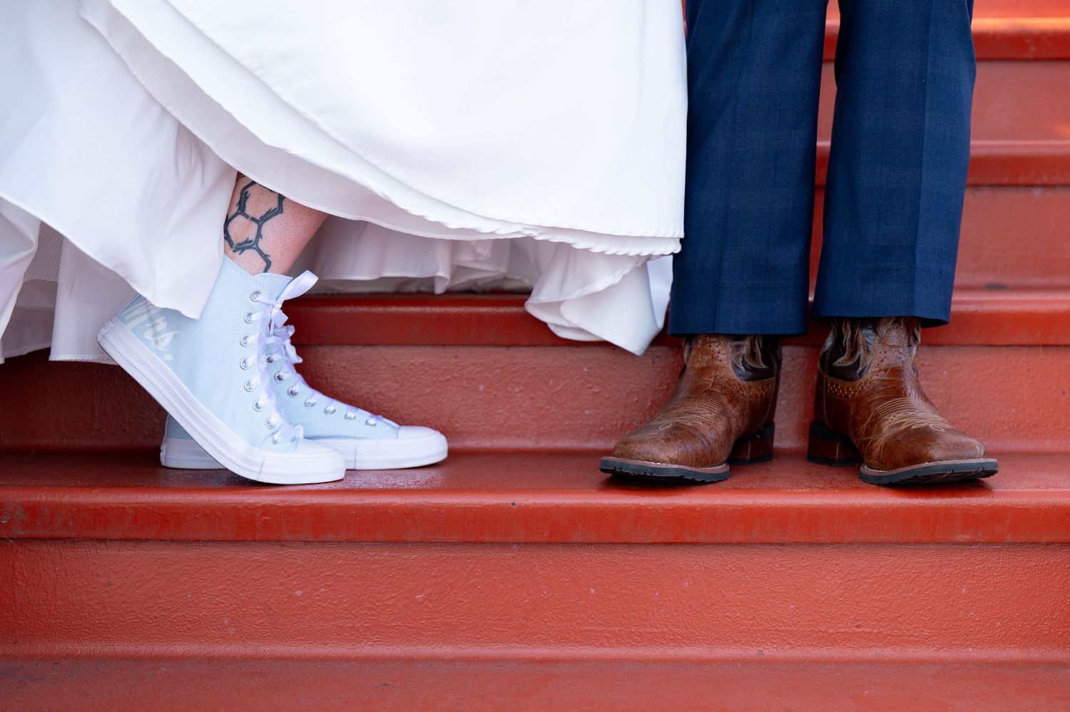 Pier B Duluth Wedding Close-up of wedding shoes showing light blue sneakers and brown dress shoes on red stairs.