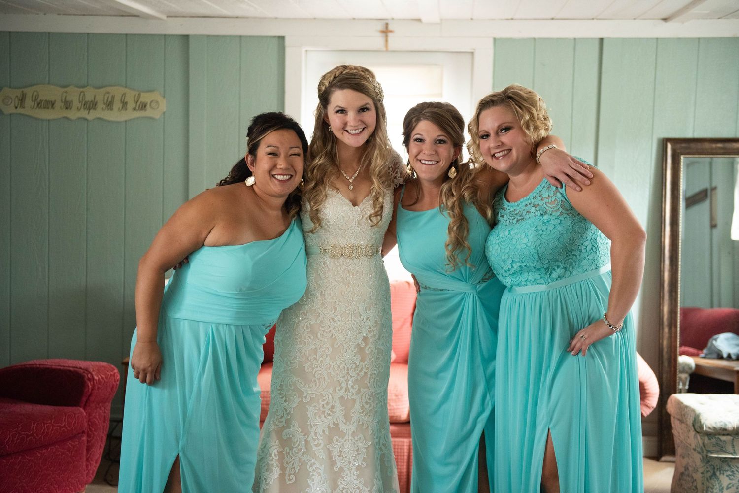 Bridesmaids in matching turquoise dresses pose with bride in white lace gown. Rum River Barn Milaca Minnesota Weddings