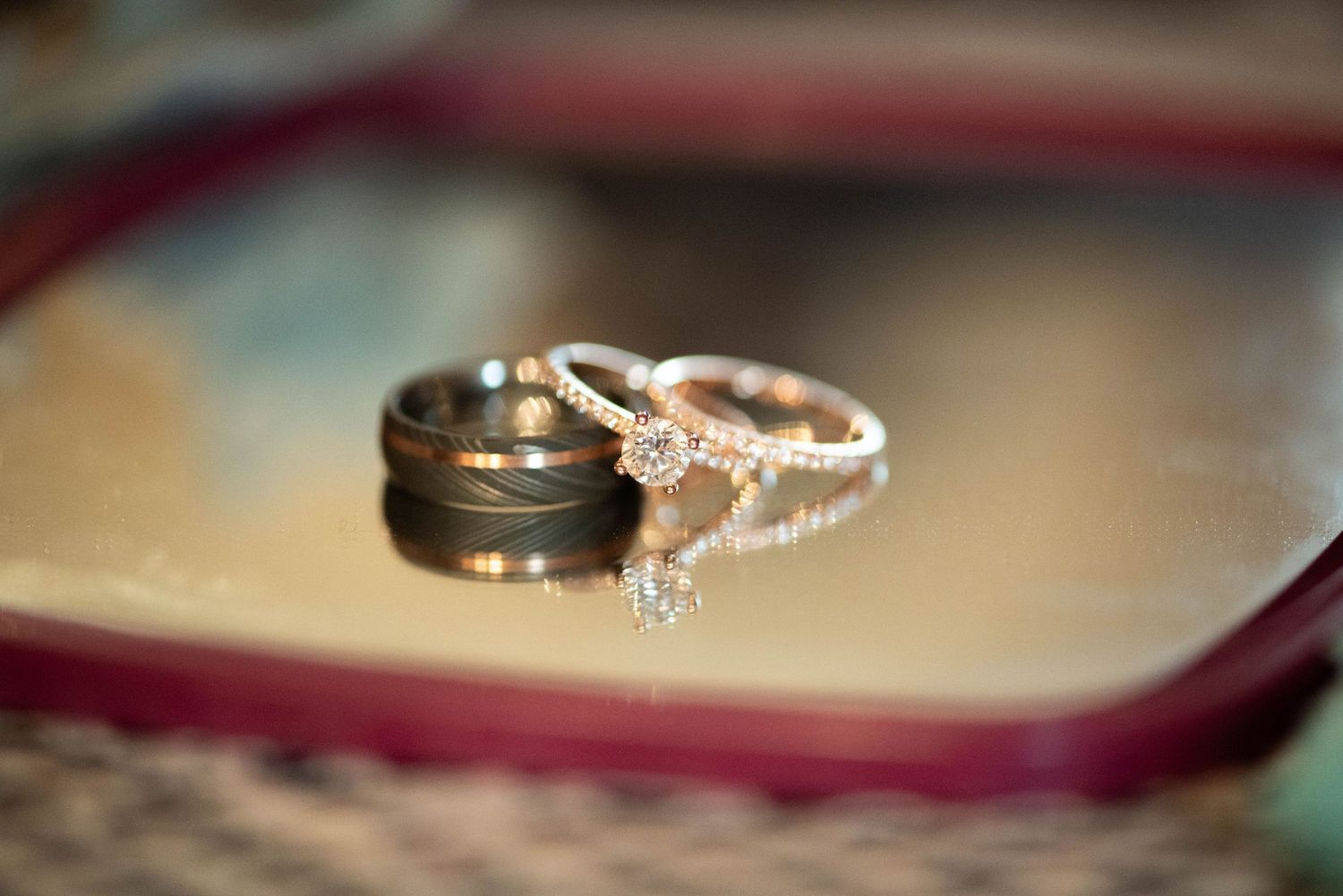 Wedding bands and engagement ring sparkle in soft focus macro photography.