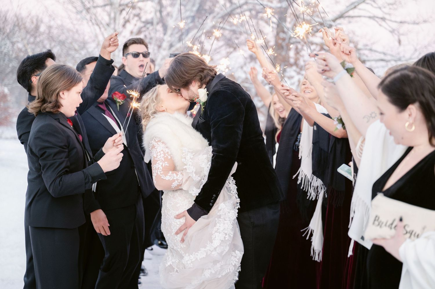 Wedding party toasts and drinks together during outdoor winter celebration against snowy scene. St Anthony weddings