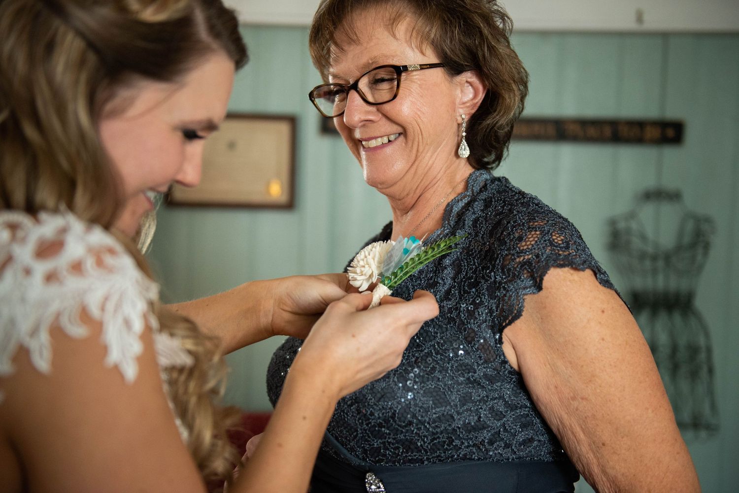 Two people share an intimate moment as one pins a corsage on the other's navy blue dress.