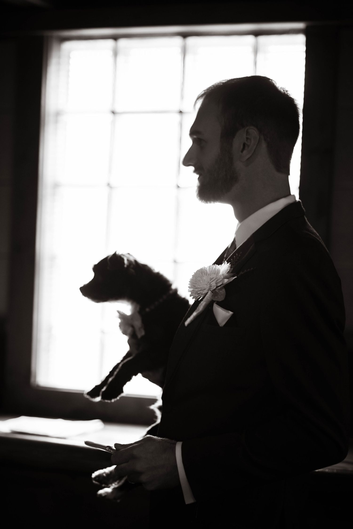 Silhouettes of people by a window in a dimly lit room create a dramatic contrast.