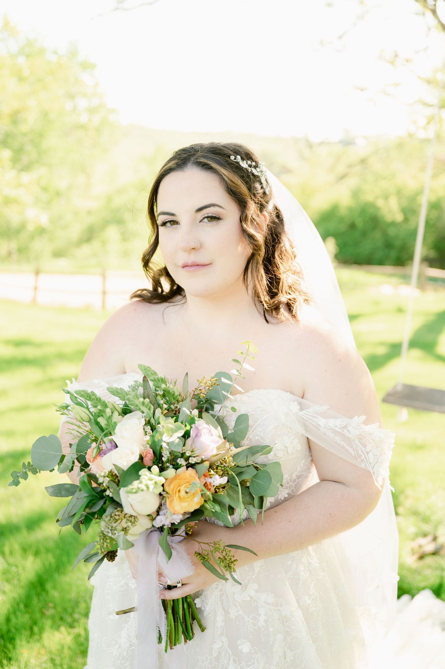Bridal portrait with pastel and greenery bouquet in a sun-drenched garden setting.