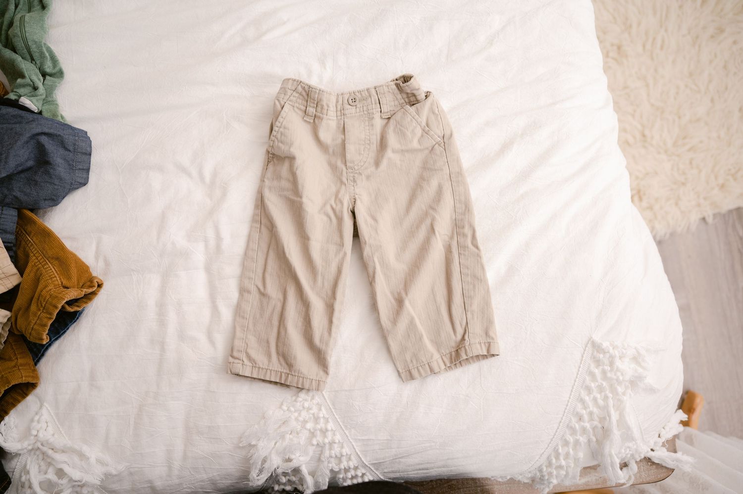 Khaki cargo capri pants laid flat on white bedding with lace trim details.