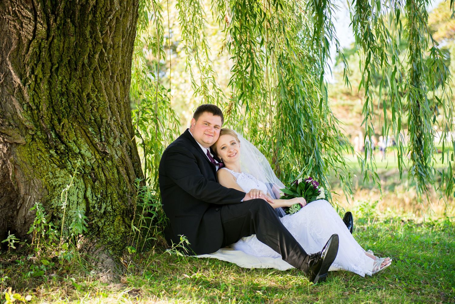 A romantic moment under a large weeping willow tree on a sunny day. Andover wedding at Magestic Oaks Golf Club