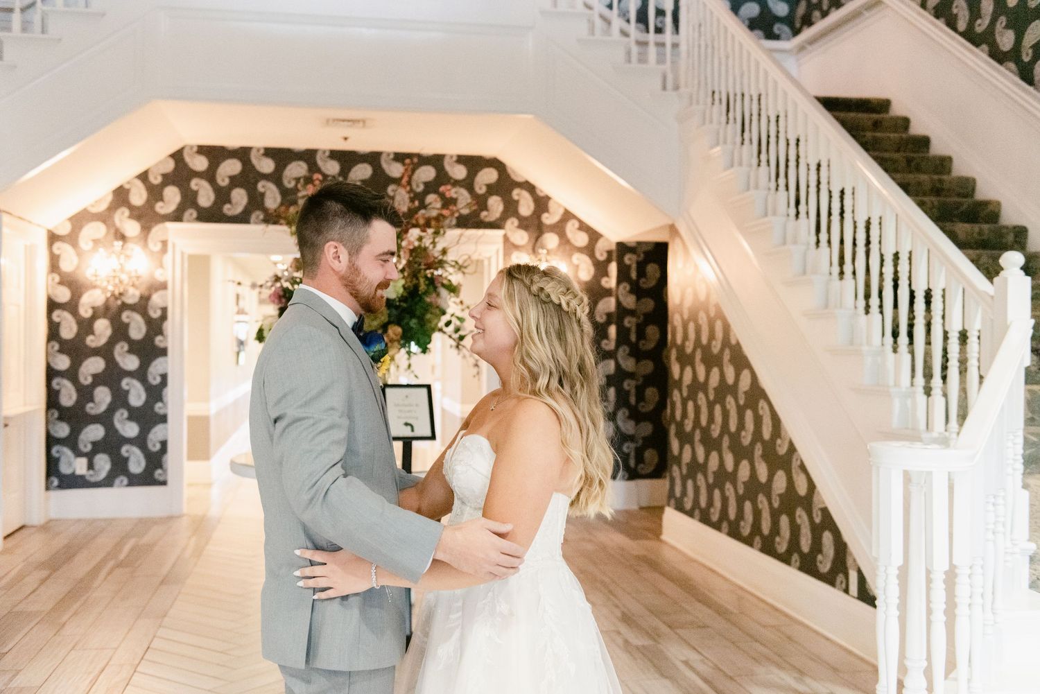 A romantic moment between a couple in formal attire beneath an archway with twinkling lights.