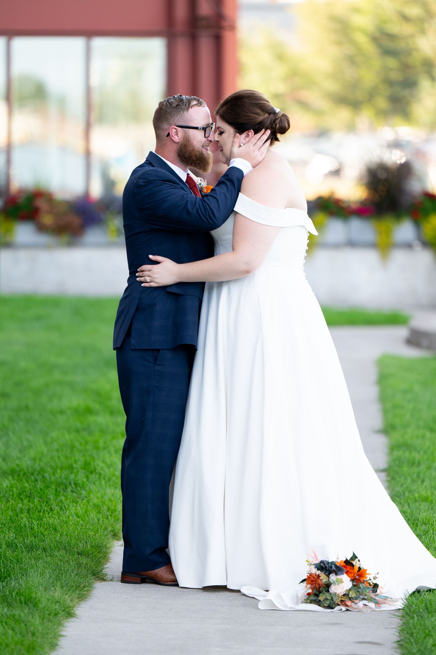 Pier B Duluth Wedding Candid sequence of wedding couple embracing on grassy lawn during outdoor photoshoot with floral bouquet.