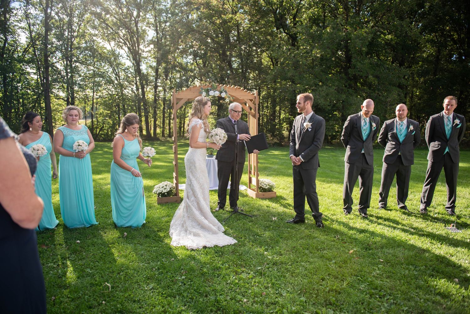 Wedding party lined up outdoors on a sunny day with bridesmaids in turquoise dresses. Rum River Barn Milaca Minnesota Weddings
