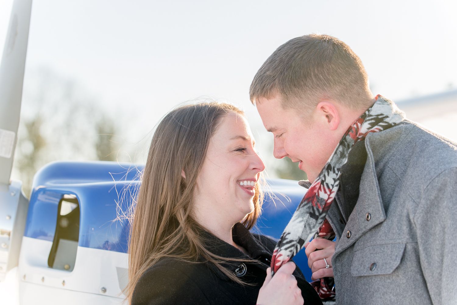 A couple enjoys a romantic winter scene with snow falling around them in soft focus.